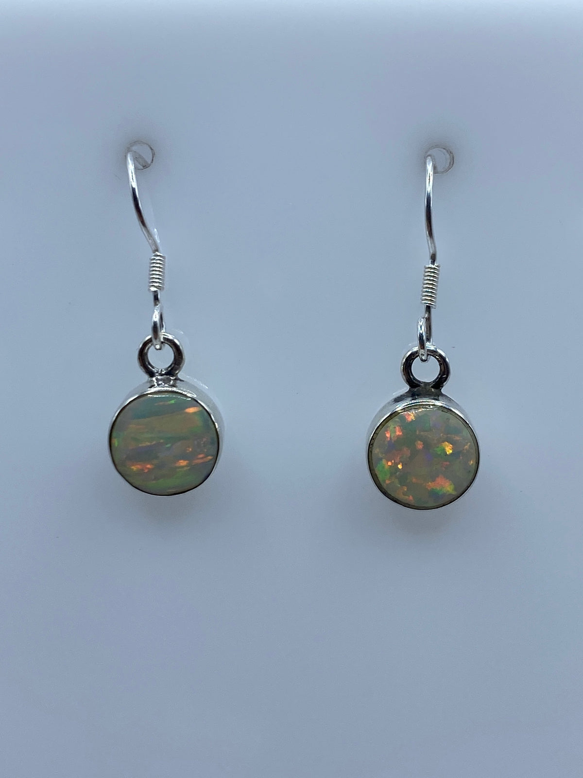 Detalle del ópalo de fuego con reflejos naranja y rojo en los aretes de plata
