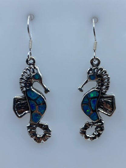 Aretes de plata 950 mostrando el color azul profundo del ópalo de fuego con efectos de luz