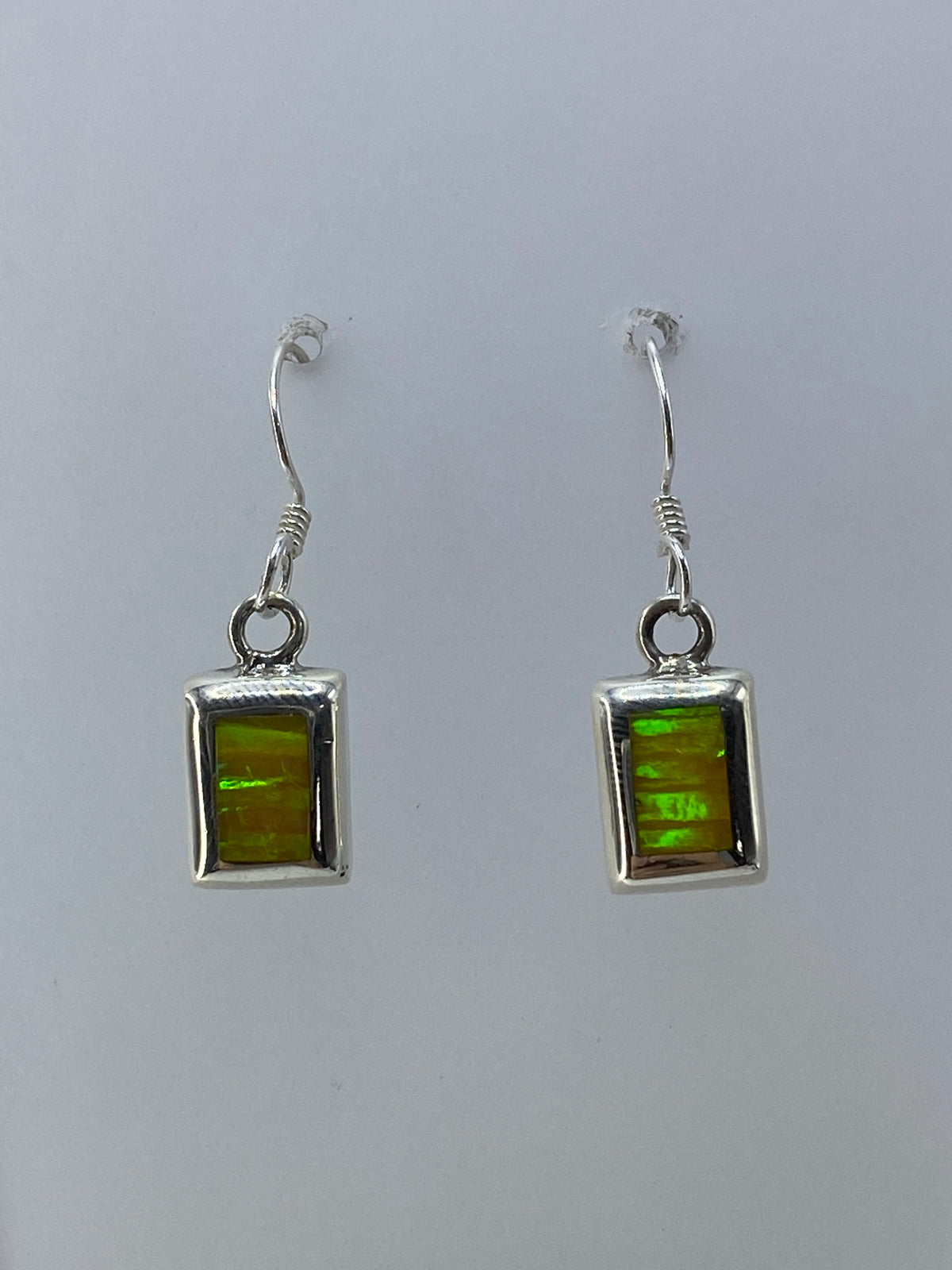 Detalle del engaste a mano del ópalo de fuego en plata, mostrando los colores iridiscentes verde y naranja