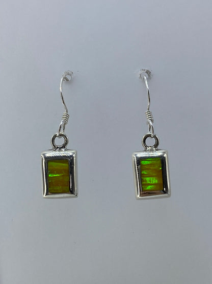 Detalle del engaste a mano del ópalo de fuego en plata, mostrando los colores iridiscentes verde y naranja