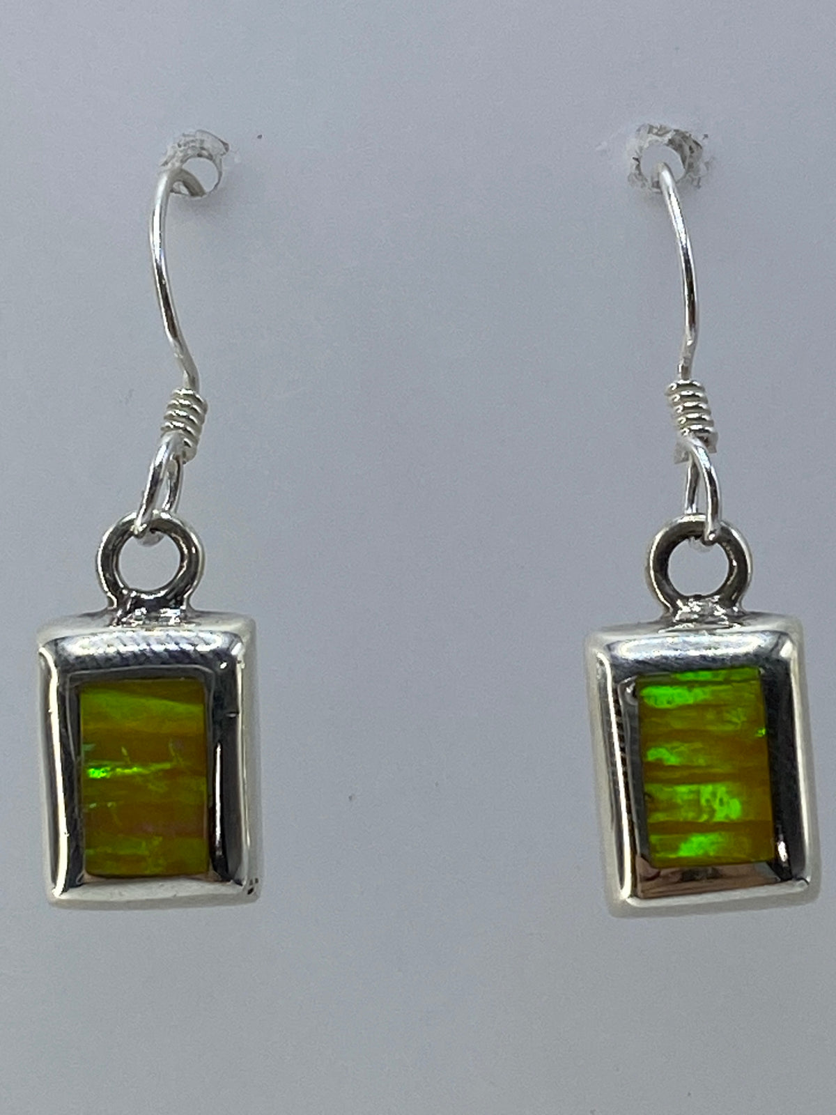Aretes de ópalo de fuego sobre fondo blanco con el sello 925 visible en la plata