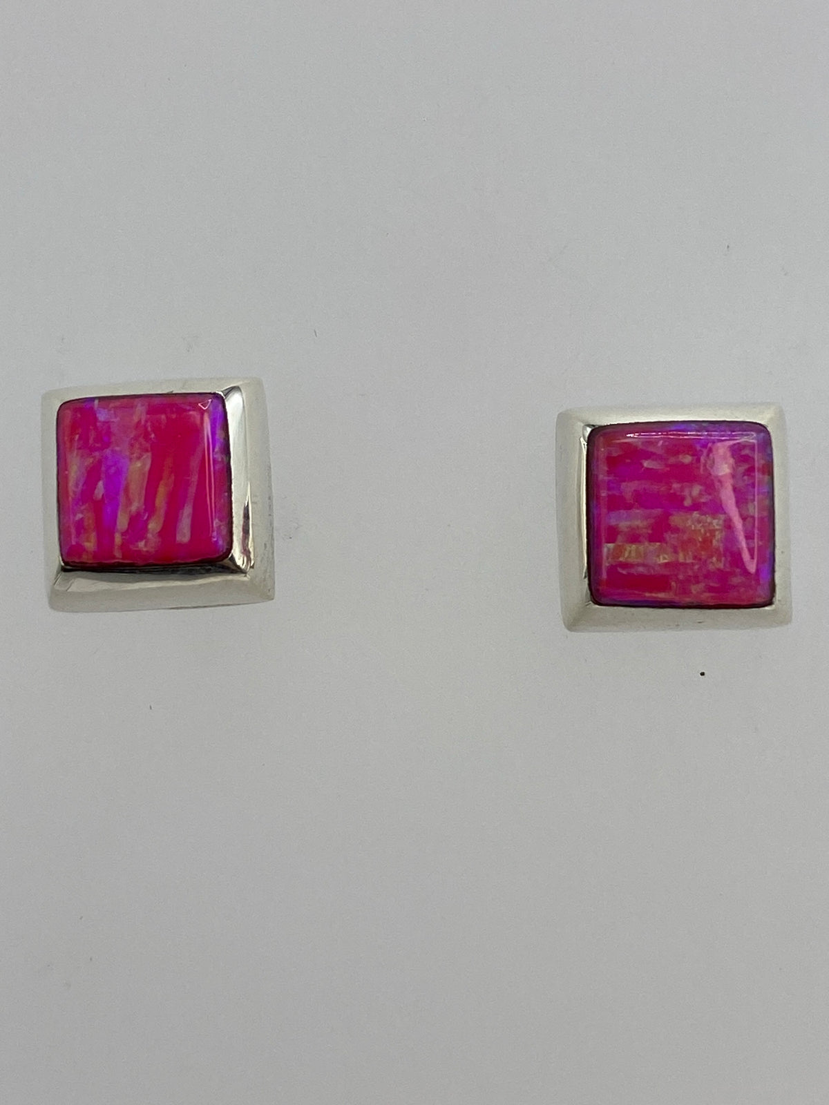 Aretes de plata con ópalo rosa sobre fondo blanco, con cierre de poste y mariposa