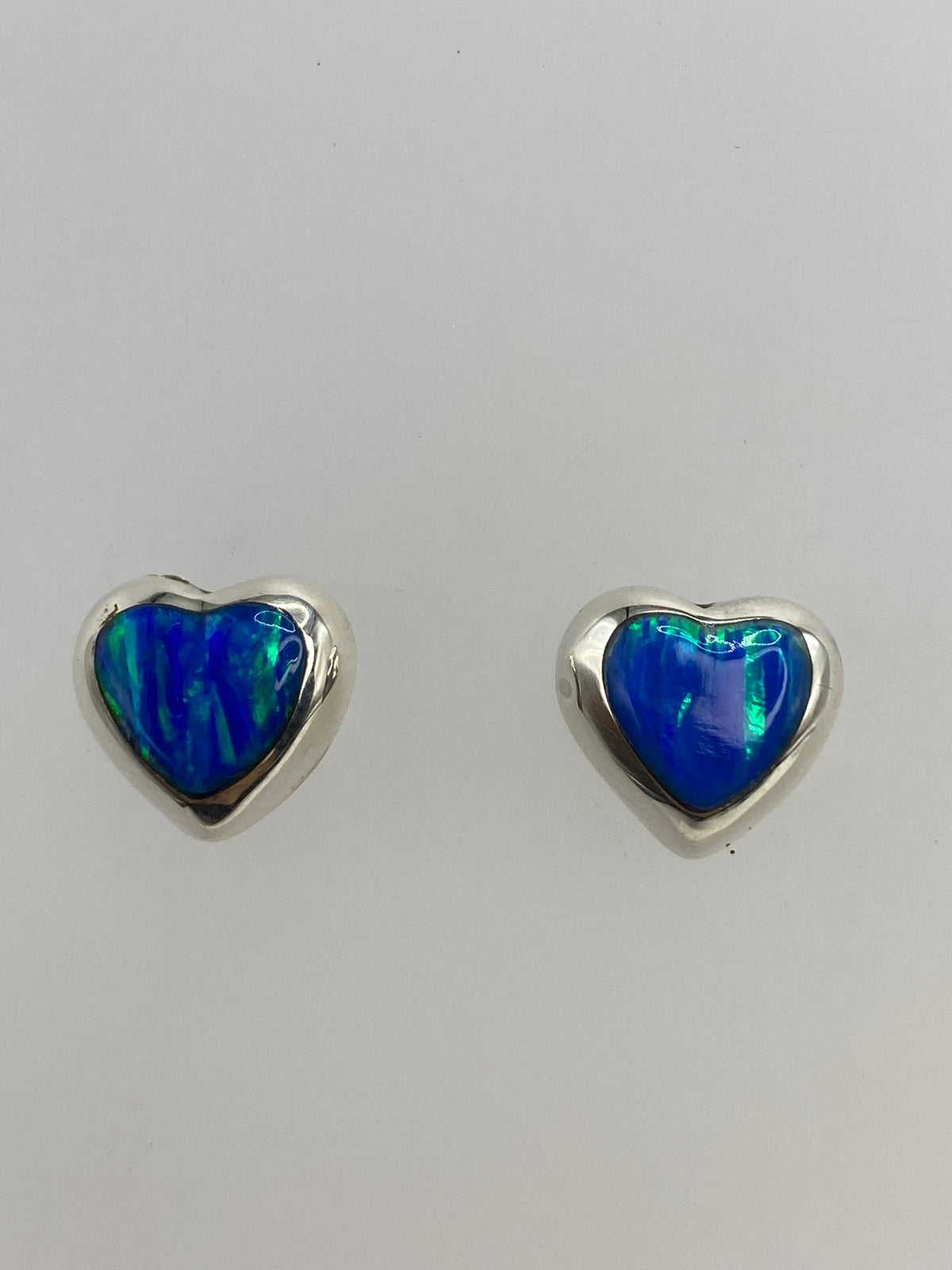 Aretes de plata con ópalo de fuego azul, engastados a mano, vista frontal del par