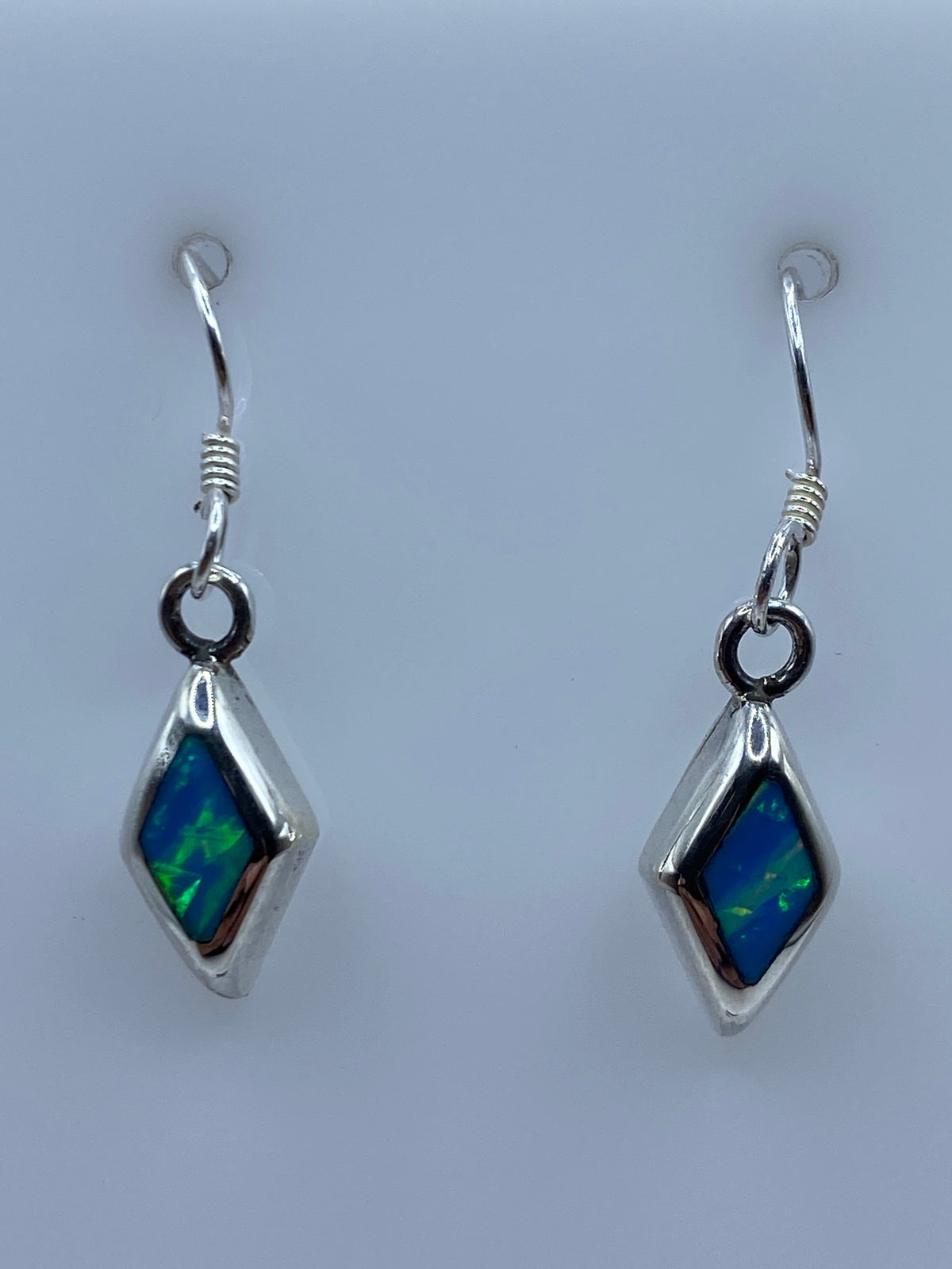 Aretes de plata con ópalo de fuego azul cielo en forma de diamante, par completo en fondo blanco