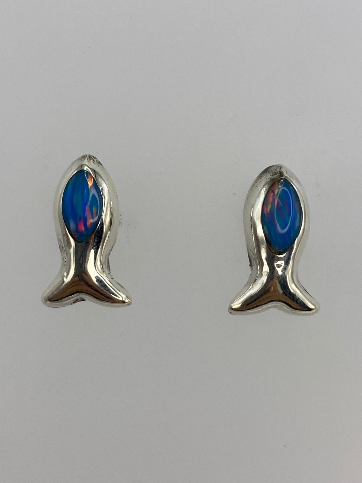 Par de aretes de plata en forma de pez con ópalo de fuego azul, vista frontal