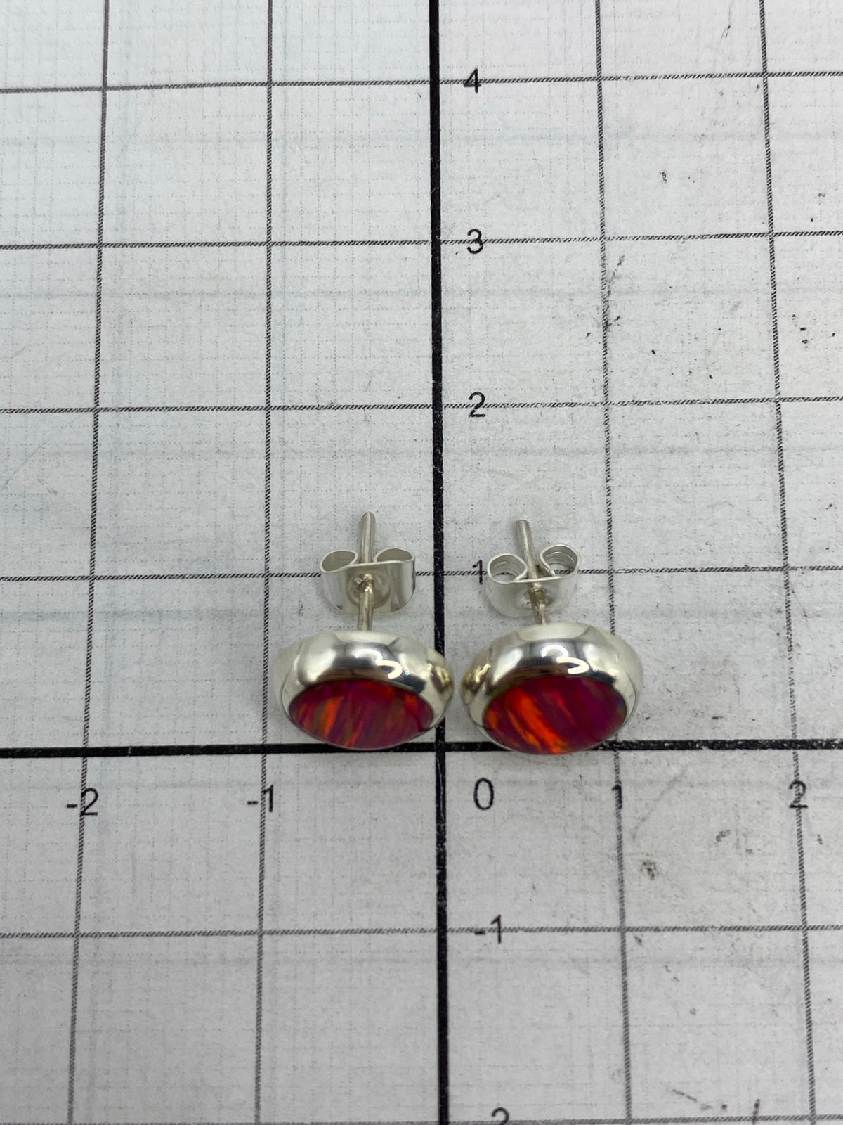 Aretes junto a referencia de tamaño (moneda) mostrando el diminuto tamaño de 1.3 cm