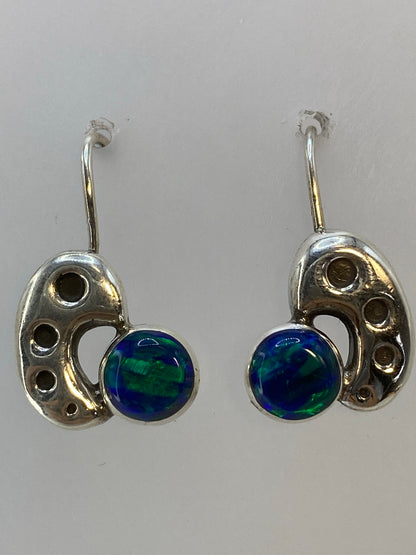 Aretes sobre fondo blanco mostrando el brillo verde del ópalo