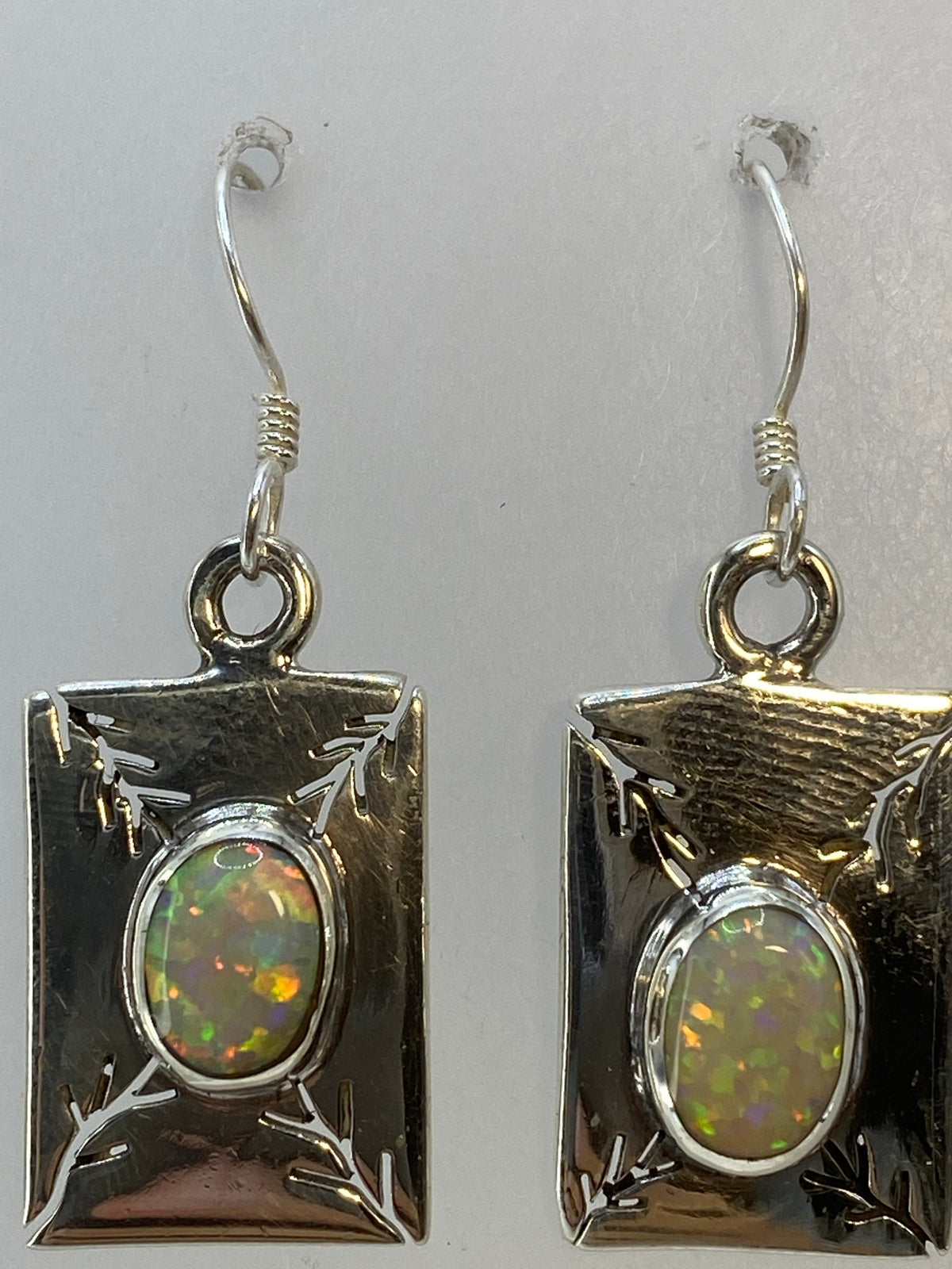 Aretes de 3.5 cm en gancho de plata, sobre fondo blanco mostrando el brillo del ópalo