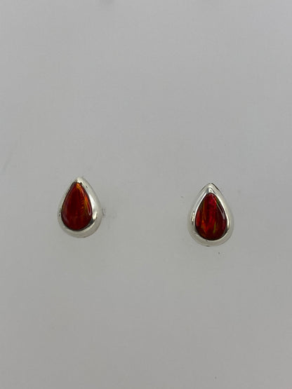 Par de aretes de plata con ópalo de fuego rojo engastado, vistos de frente sobre fondo blanco
