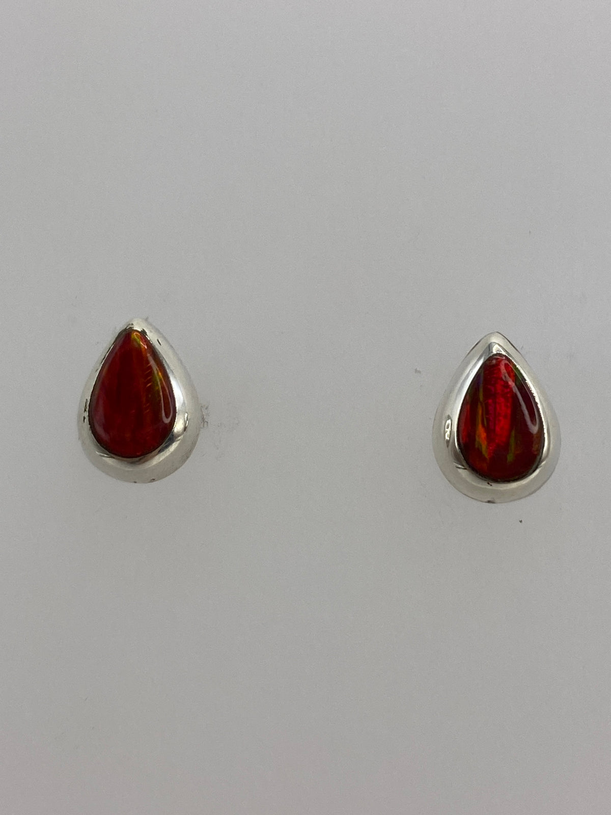 Detalle de un arete mostrando el engaste a mano del ópalo rojo en la plata 925