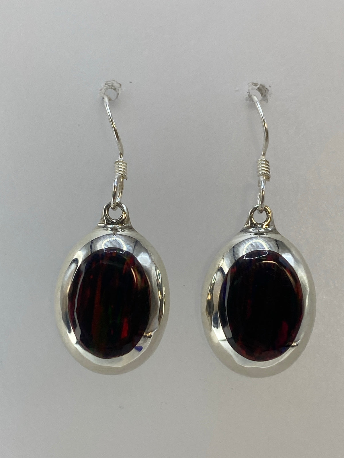 Par de aretes de plata 925 con ópalo de fuego multicolor, colgando sobre fondo blanco