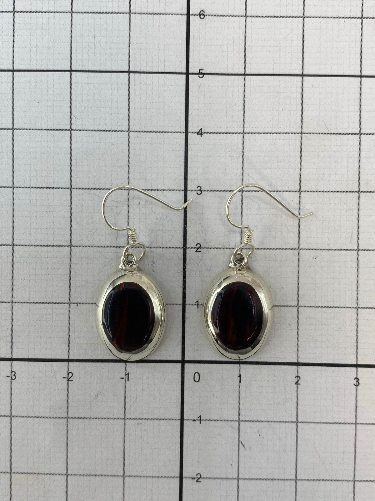 Aretes de ópalo de fuego sobre regla mostrando largo de 3 cm