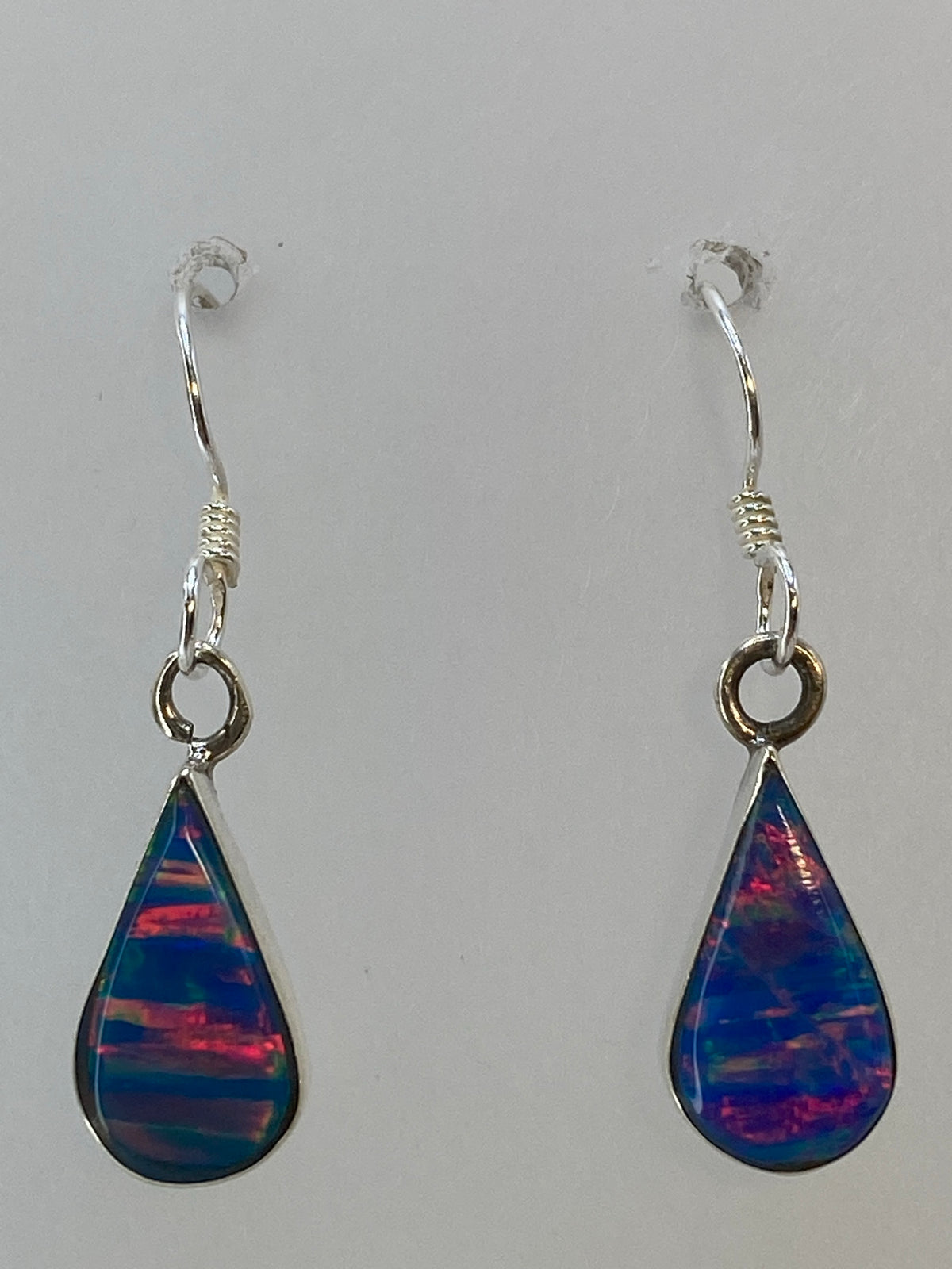 Aretes de ópal de fuego colgando, iluminando los reflejos del color