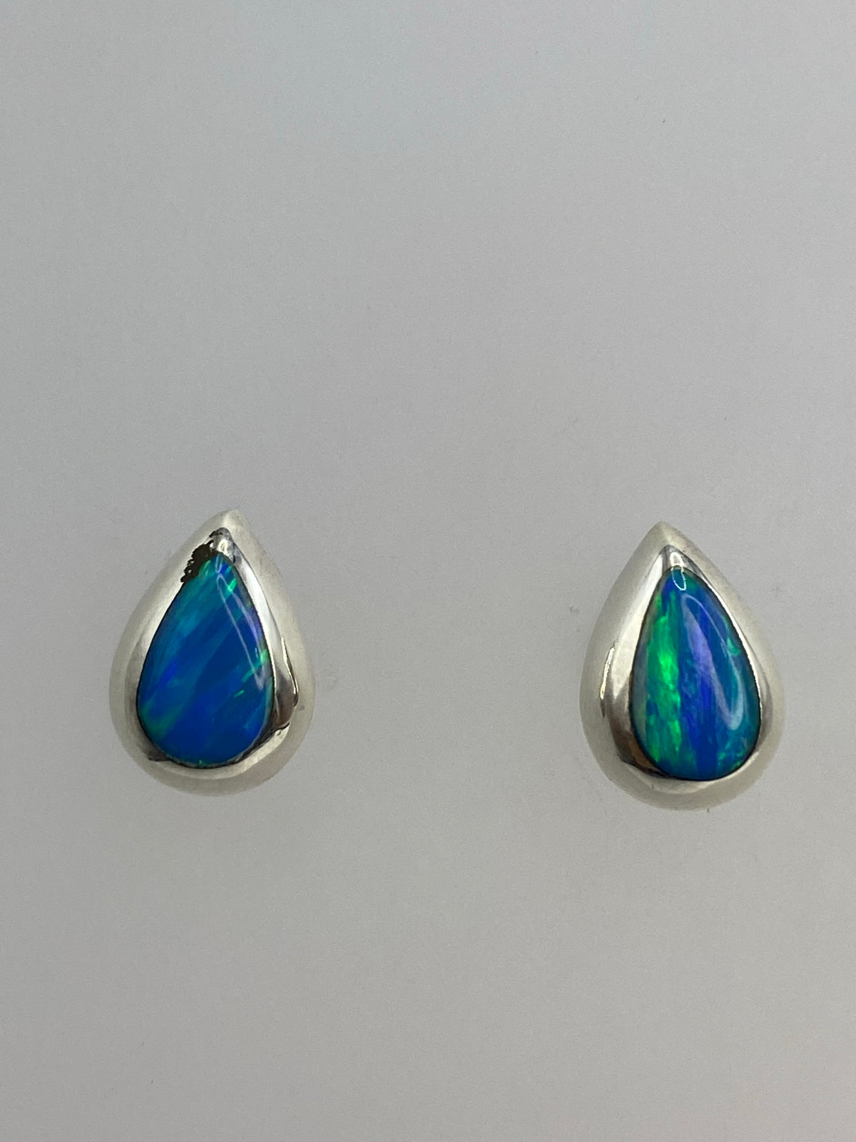 Aretes de ópalo de fuego en la mano, mostrando el tamaño delicado de 1.3 cm