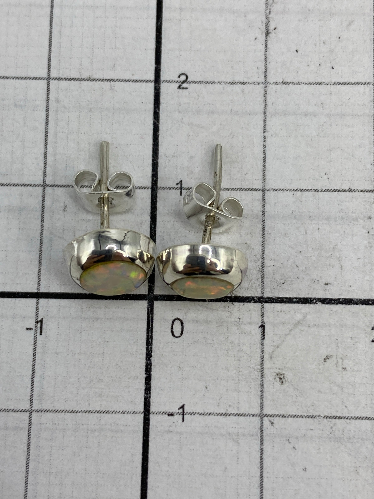 Aretes de plata con ópalo de fuego vistos desde atrás, mostrando los postes de plata y el Quinto 925