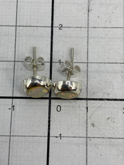 Aretes de plata con ópalo de fuego vistos desde atrás, mostrando los postes de plata y el Quinto 925