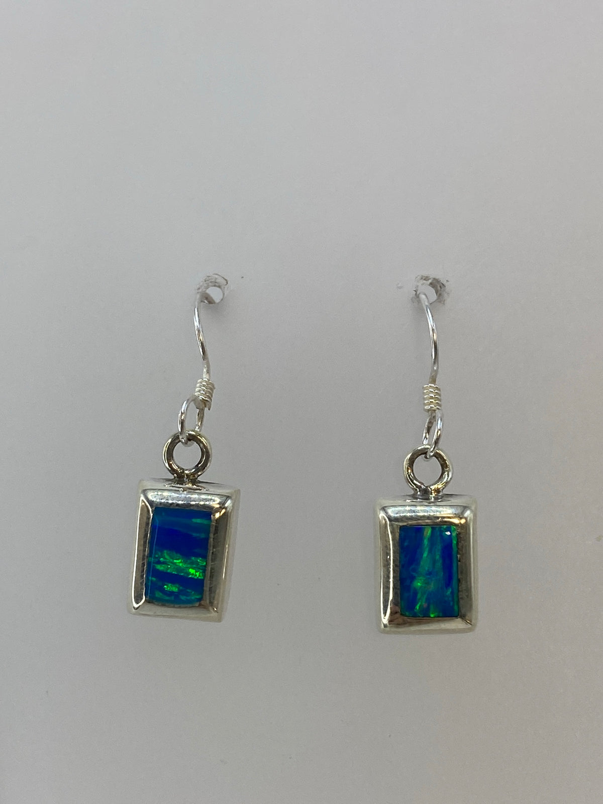 Aretes vistos de frente mostrando la piedra verde limon engastada en marco de plata