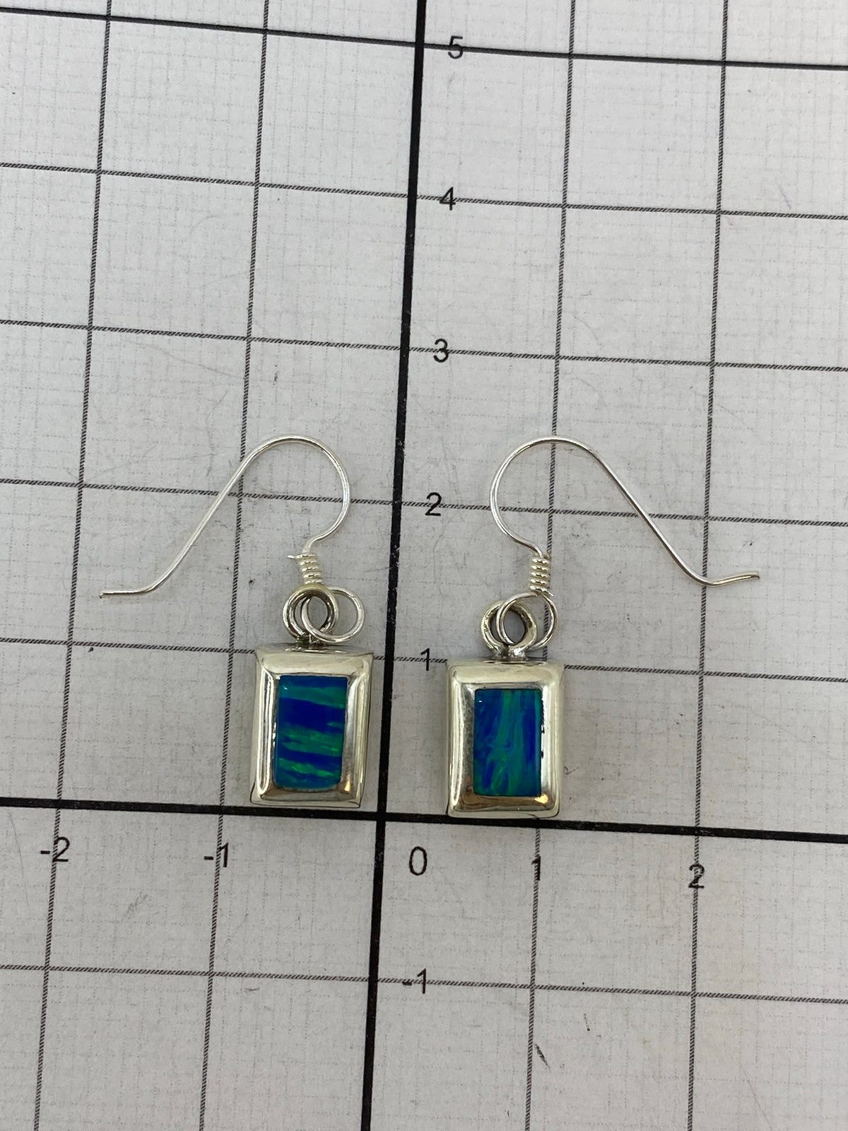 Aretes sobre regla de medicion mostrando los 2.5 cm de largo