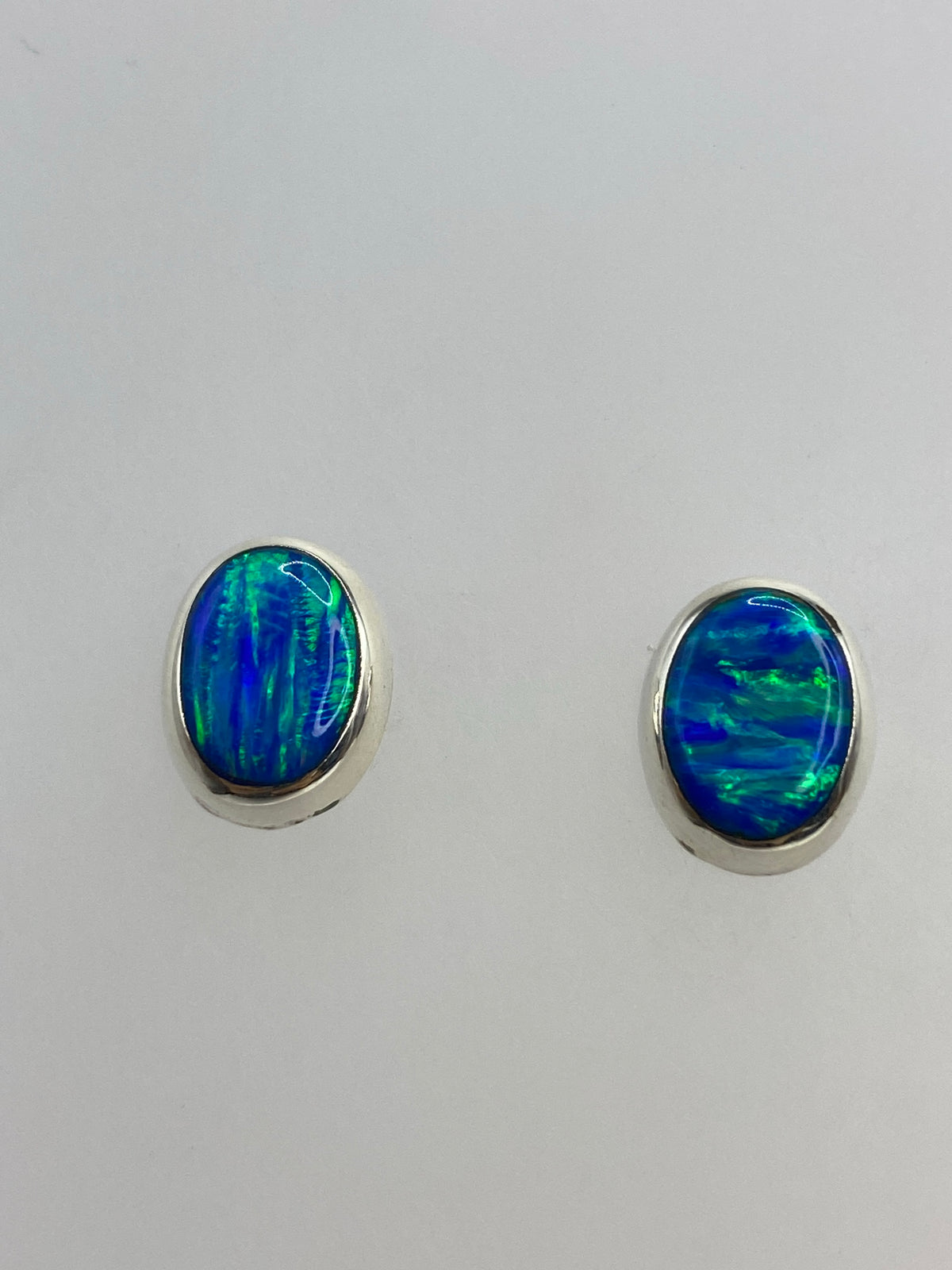 Detalle del ópalo de fuego azul en cada arete, mostrando los reflejos verdes