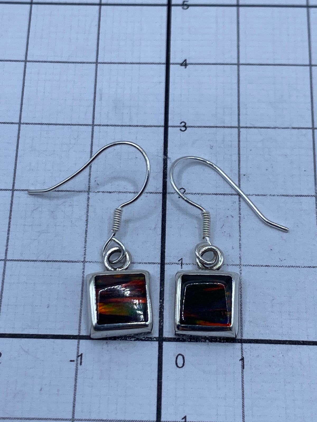 Aretes en estuche azul mostrando peso de 1.4 gramos en báscula