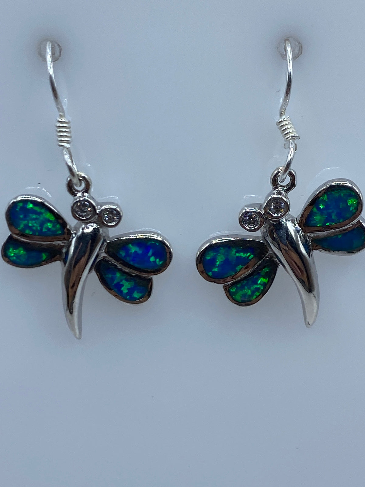Aretes sobre fondo blanco mostrando el brillo azul del Ópalo