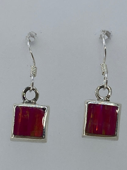 Aretes sobre fondo blanco mostrando el brillo rosa del ópalo de fuego