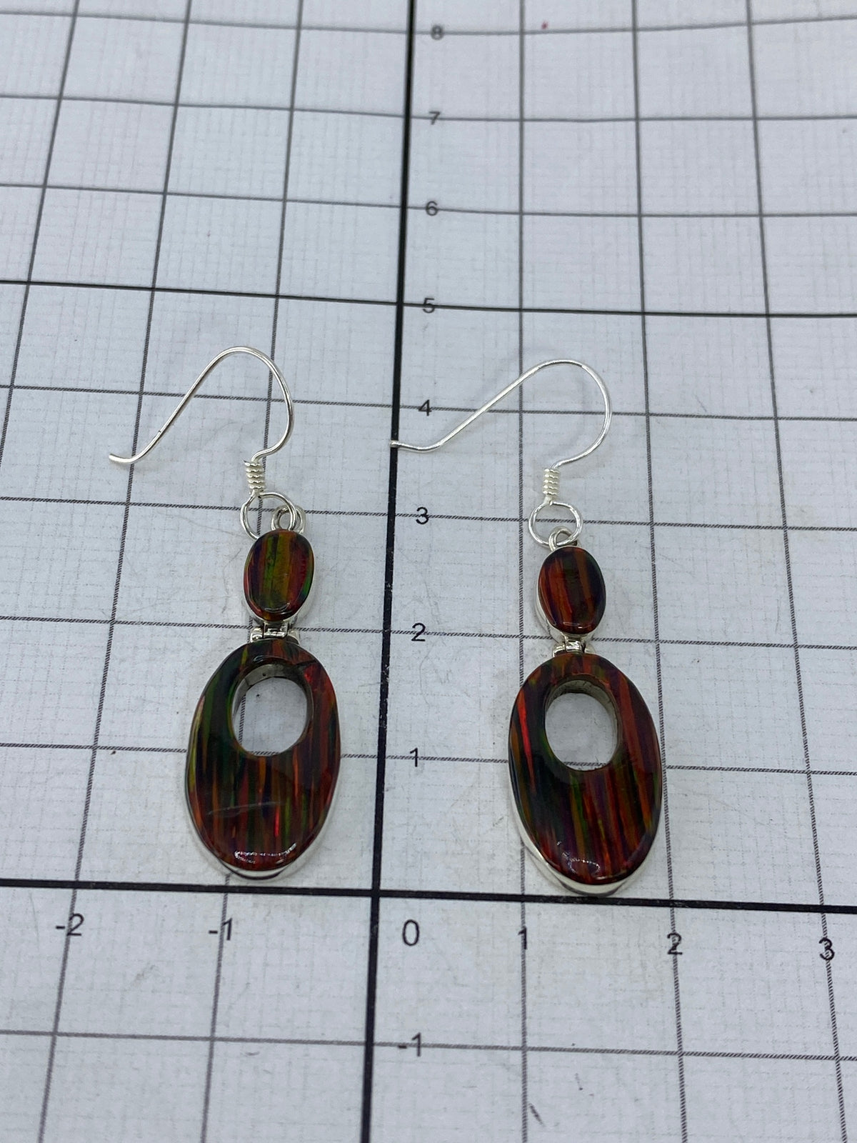 Aretes de plata 950 con opalo de fuego bajo luz natural, reflejando colores rojo, naranja, verde y azul