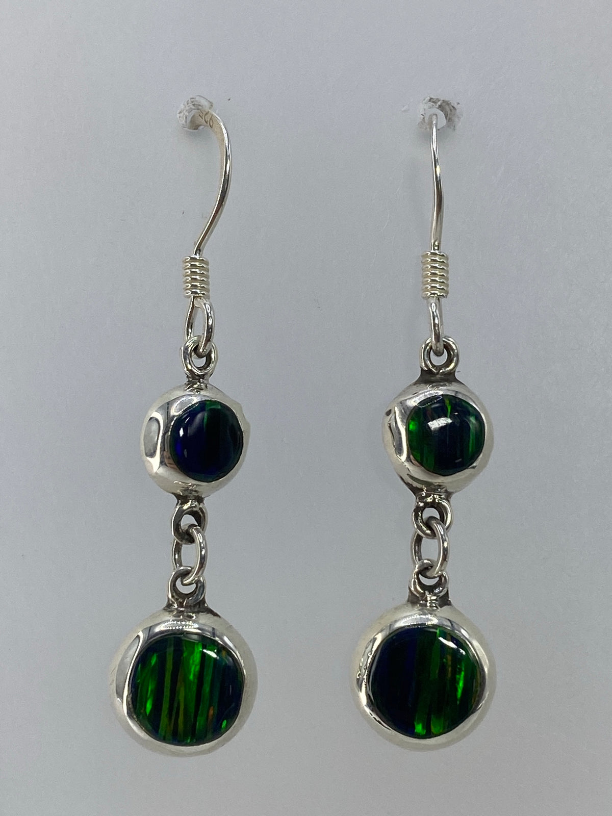 Par de aretes de plata con ópalo de fuego multicolor sobre fondo blanco