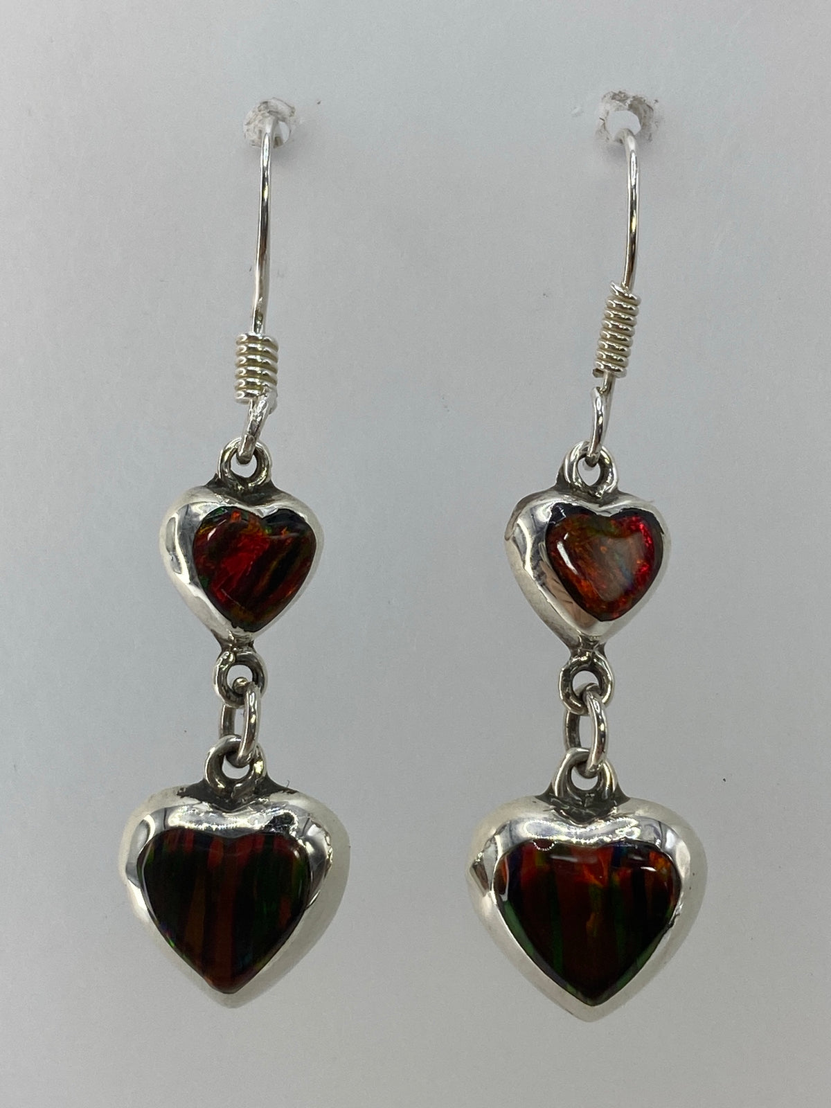 Par de aretes de plata con ópalo de fuego multicolor colgando del lóbulo