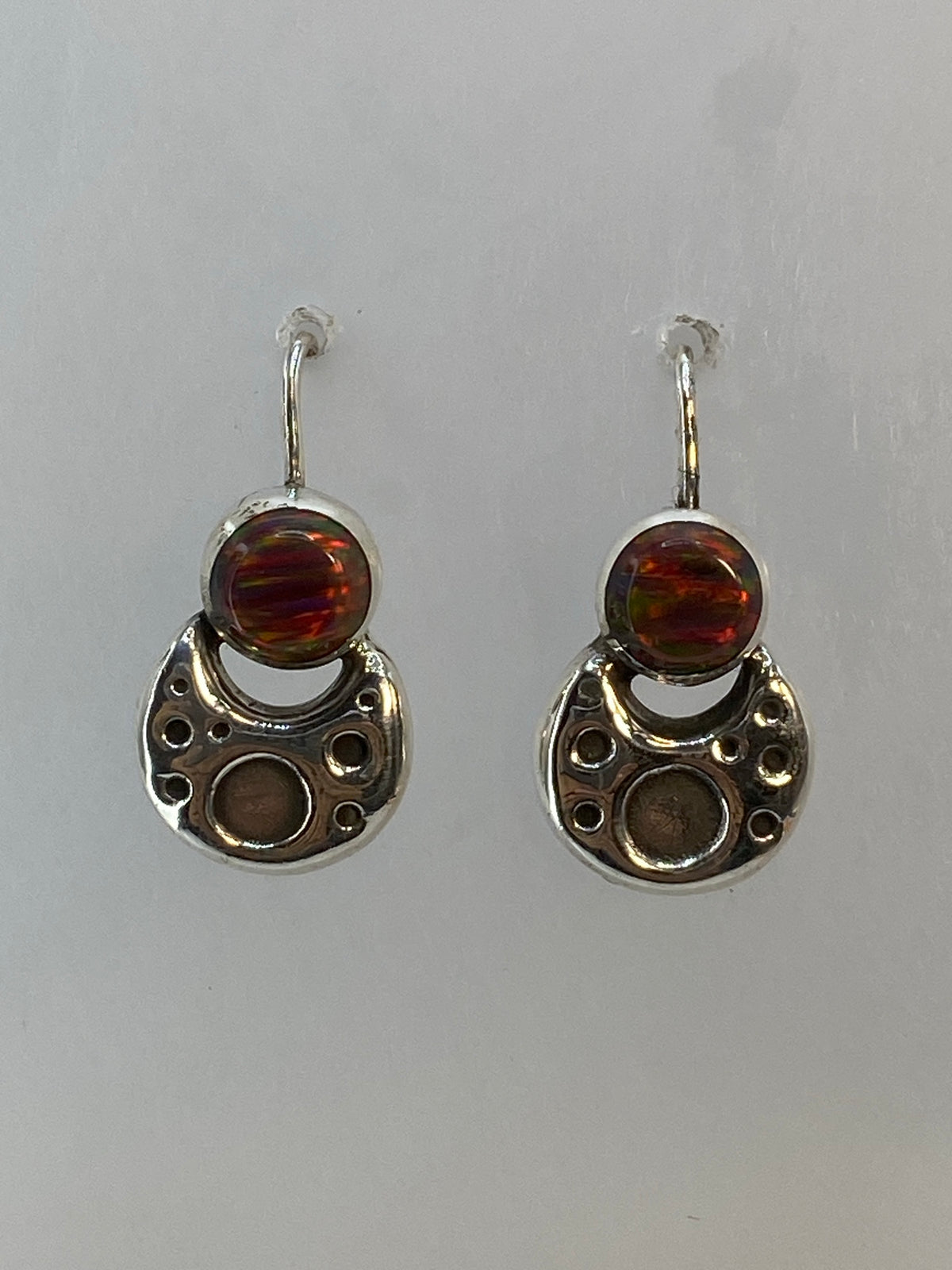 Detalle del engaste a mano del ópalo de fuego en plata, mostrando los colores rojo, naranja y verde