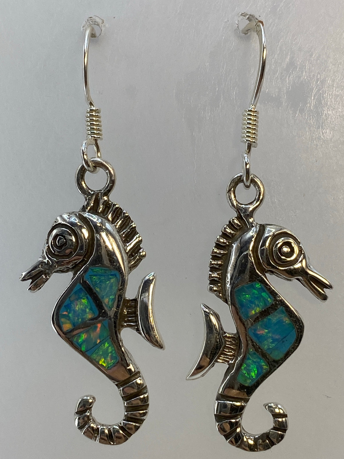 Aretes de plata colgando, vista frontal del par completo en tonos azul cielo