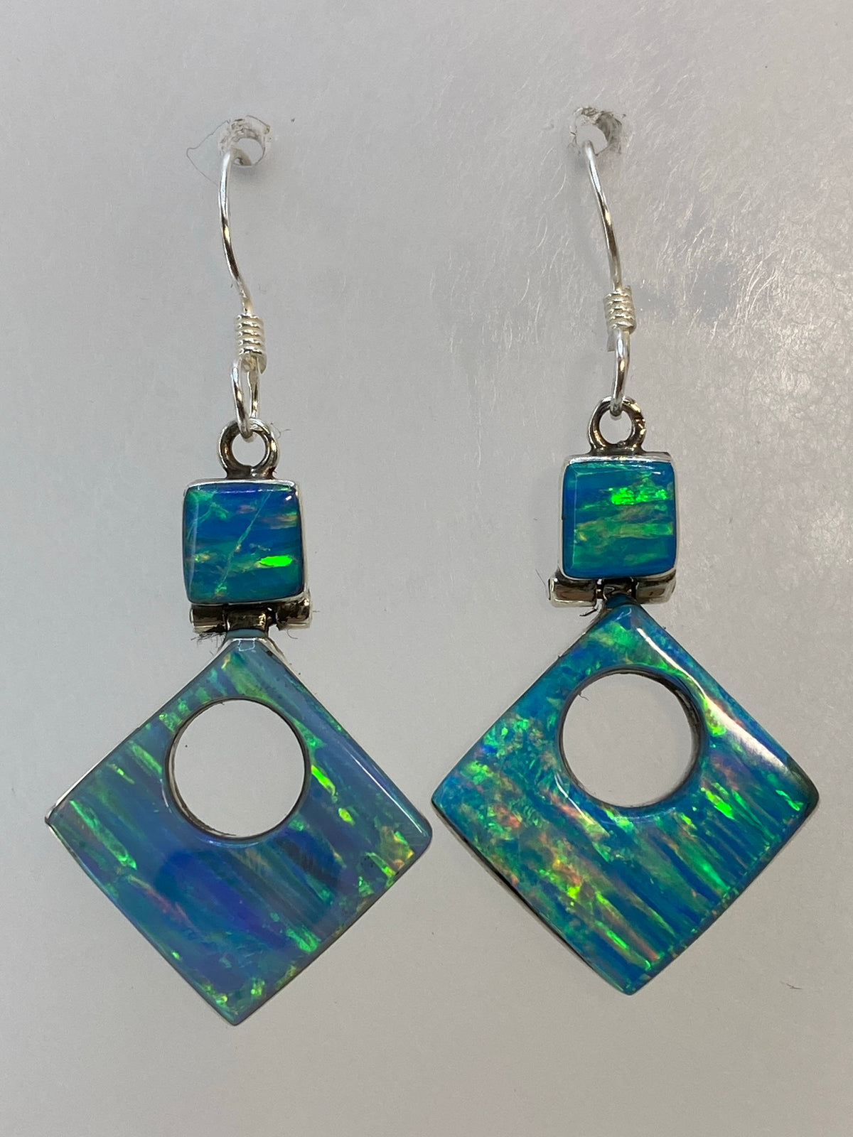 Par de aretes de plata con opalo de fuego multicolor, colgando en gancho de plata