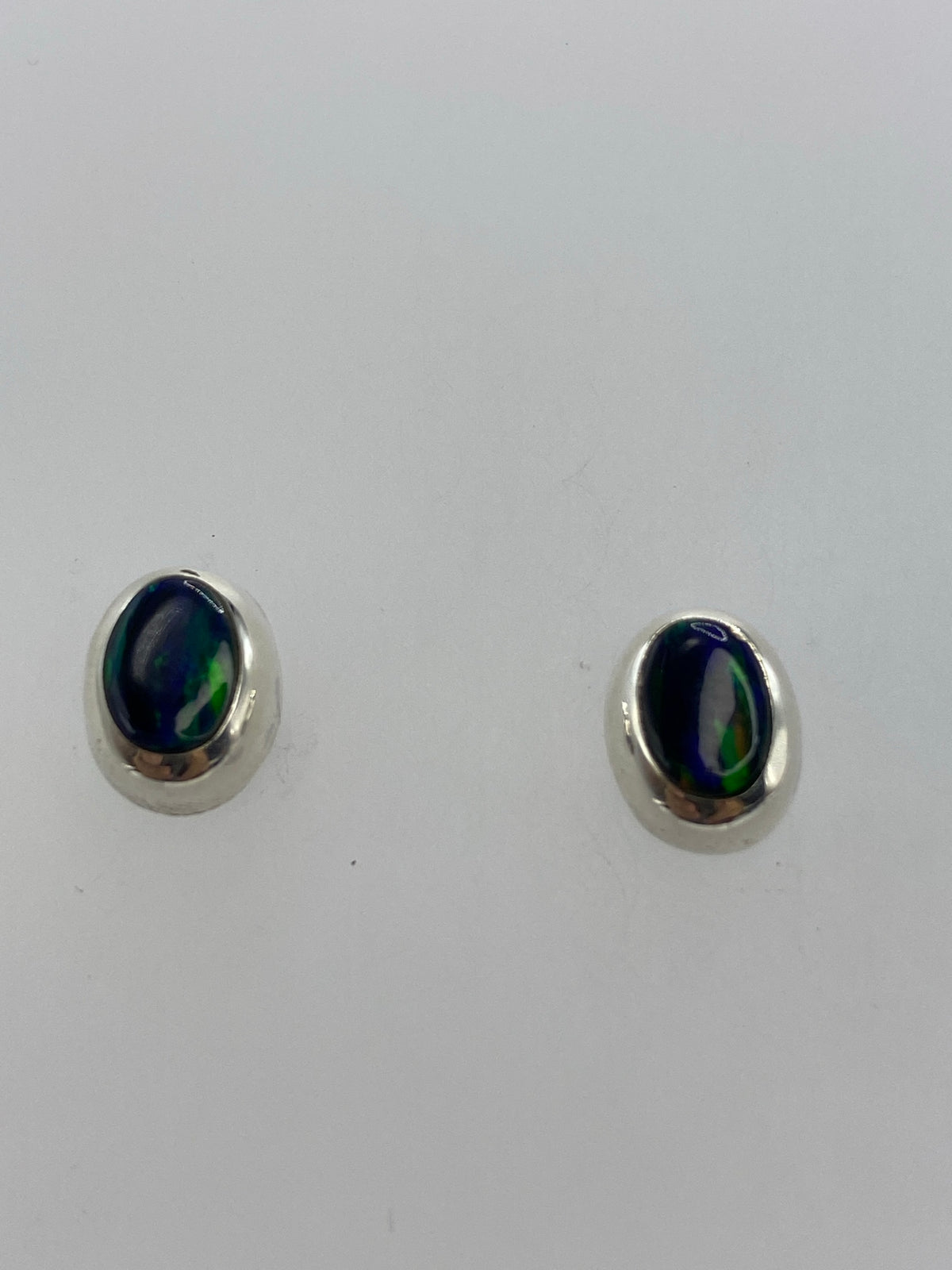 Vista frontal del par de aretes con ópalo multicolor en tonos verde, naranja y rojo