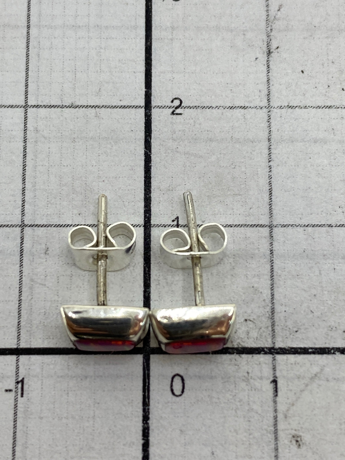 Aretes sobre balanza mostrando el peso total de 0.8 g con sello 925