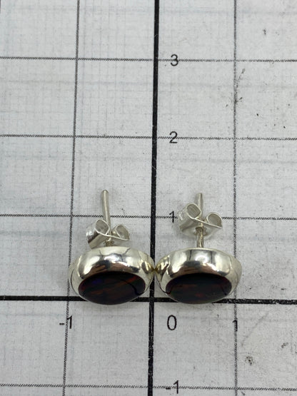Aretes pequeños sobre fondo claro destacando el color morado del ópalo