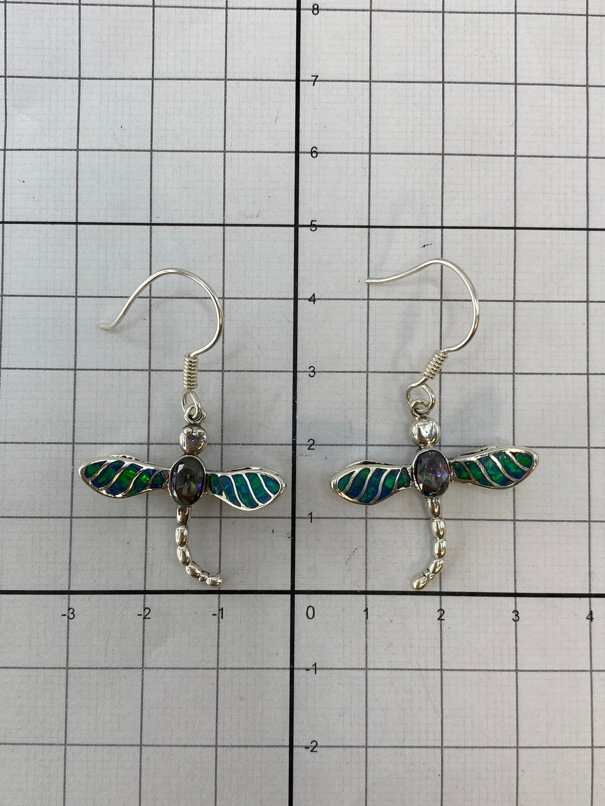 Aretes puestos en oreja, mostrando el largo de 4.2 cm y el reflejo multicolor del ópalo