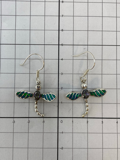 Aretes puestos en oreja, mostrando el largo de 4.2 cm y el reflejo multicolor del ópalo