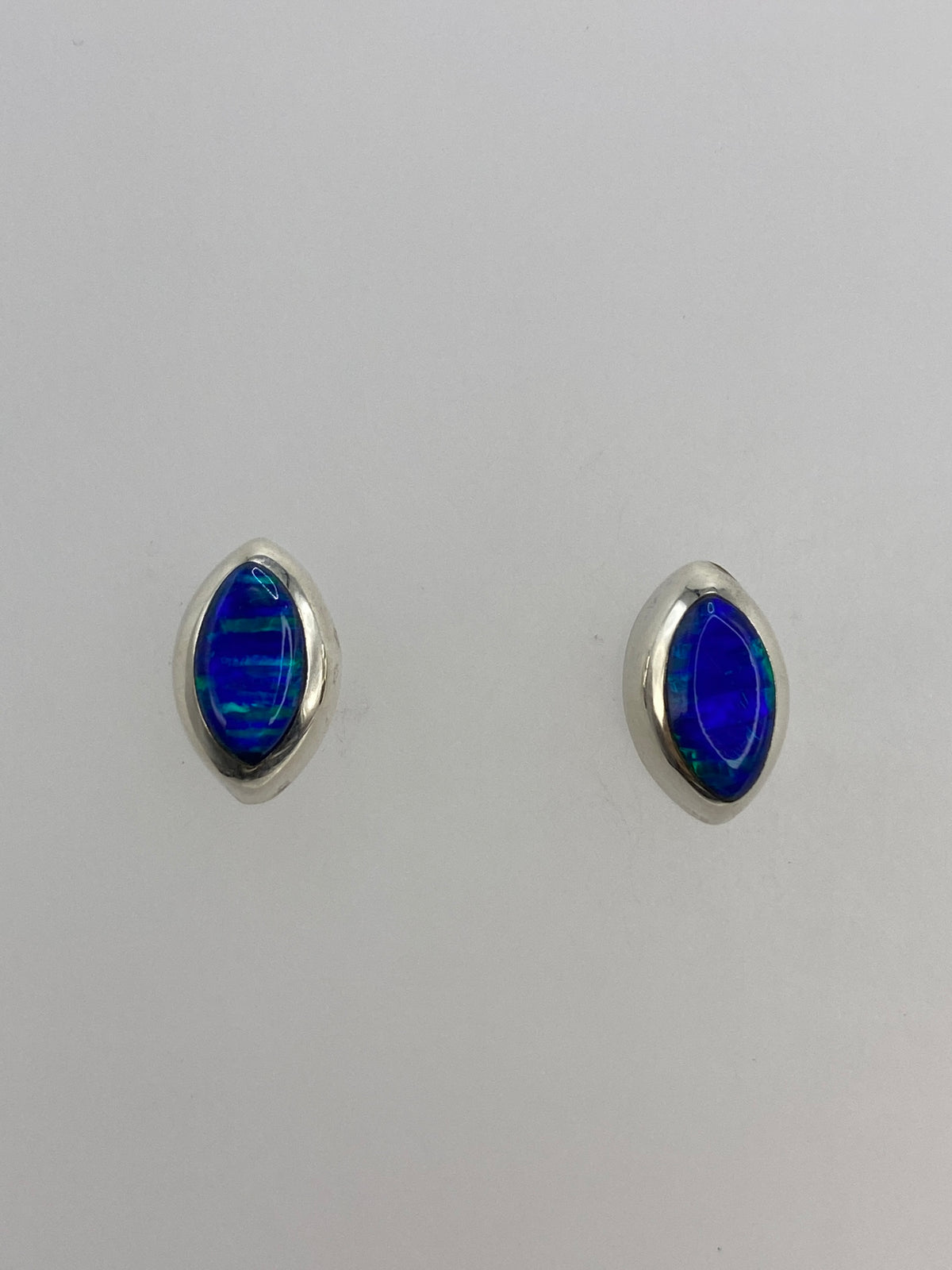 Par de aretes de plata con opalo de fuego azul, vista frontal mostrando la piedra engastada