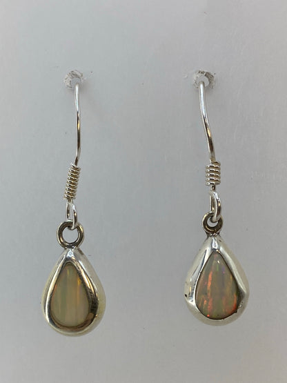 Par de aretes de plata 925 con ópalo de fuego multicolor, colgando sobre fondo blanco