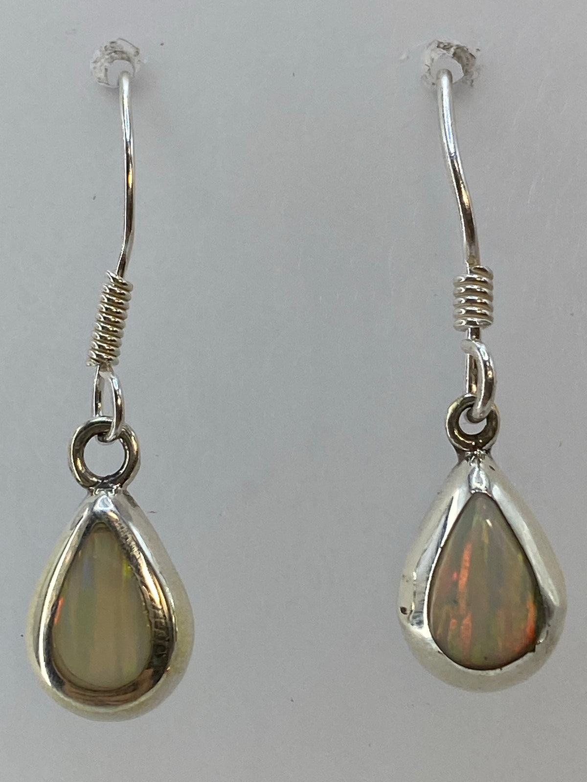 Aretes de plata con ópalo de fuego mostrando los tonos amarillo, naranja y rojo