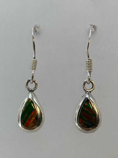 Aretes de plata con ópalo de fuego verde en forma de gota, colgando sobre fondo blanco