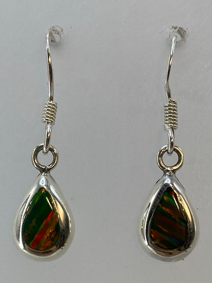 Aretes de plata 925 con ópalo de fuego sobre tela azul, mostrando el juego de colores