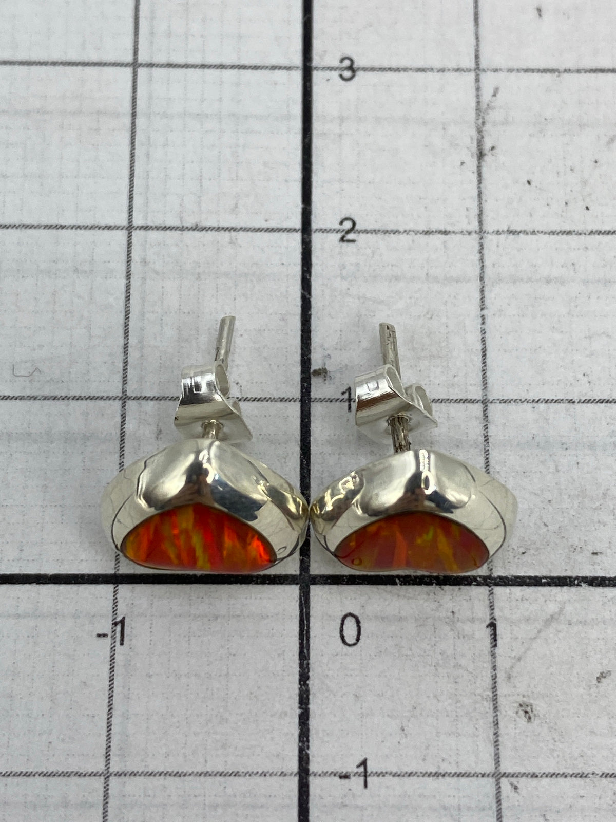 Aretes puestos en oreja mostrando el brillo del Ópalo de Fuego