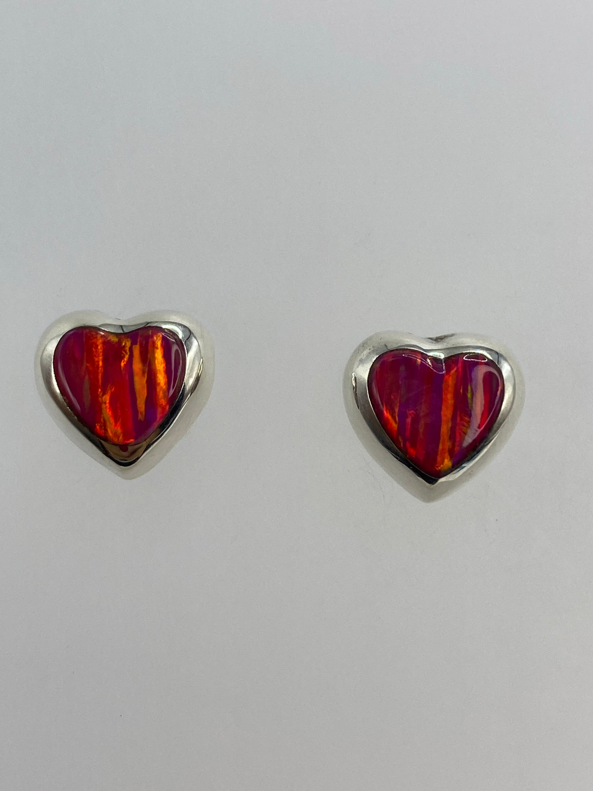 Par de aretes de plata 925 con opalo de fuego rosa en forma de gotas frente a fondo gris
