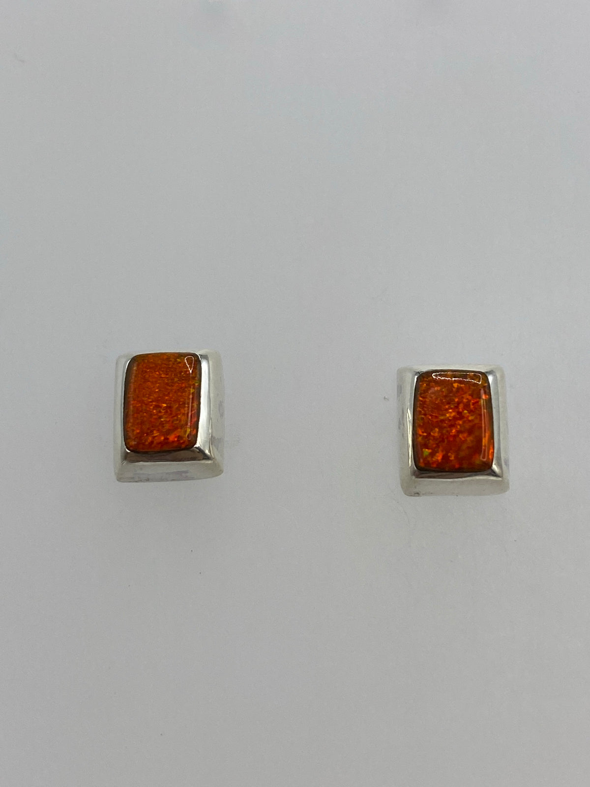 Detalle frontal de los aretes de ópalo de fuego con brillo naranja cálido