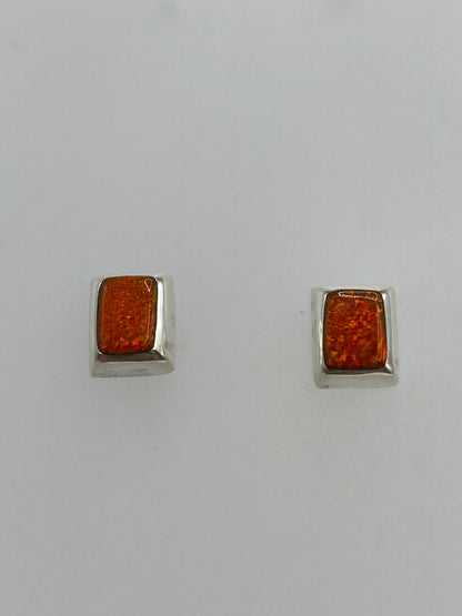 Detalle frontal de los aretes de ópalo de fuego con brillo naranja cálido