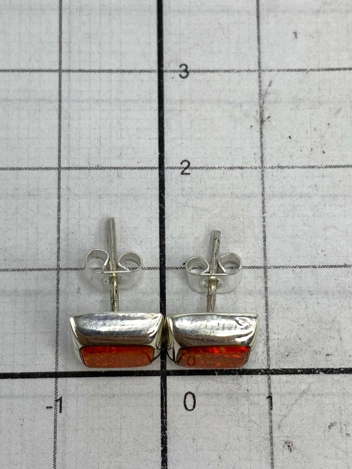 Aretes sobre fondo blanco destacando el color naranja luminoso de la piedra