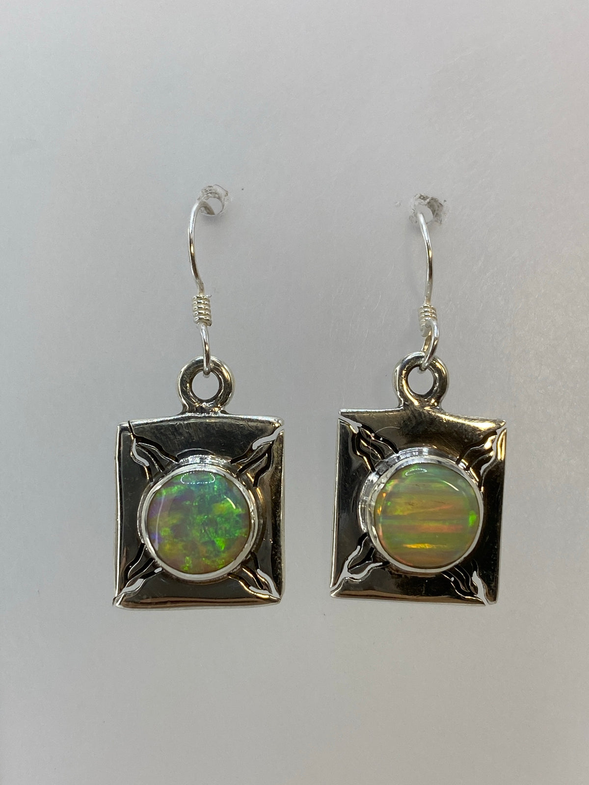 Aretes de plata en ópalo fuego mostrando reflejos verdes, amarillos y naranjas