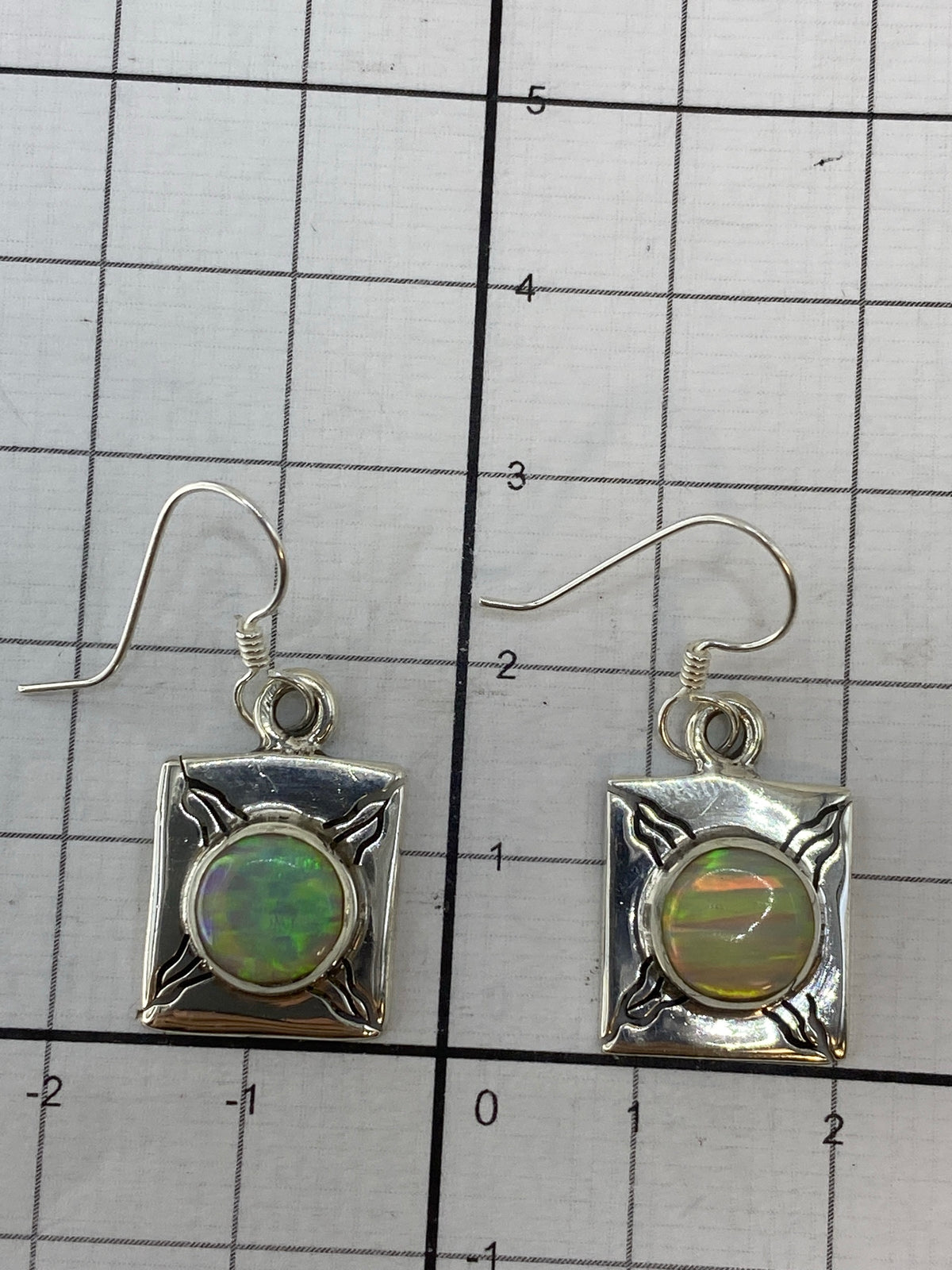 Aretes de ópalo de fuego en gancho de plata 950 sobre fondo blanco con Quinto visible