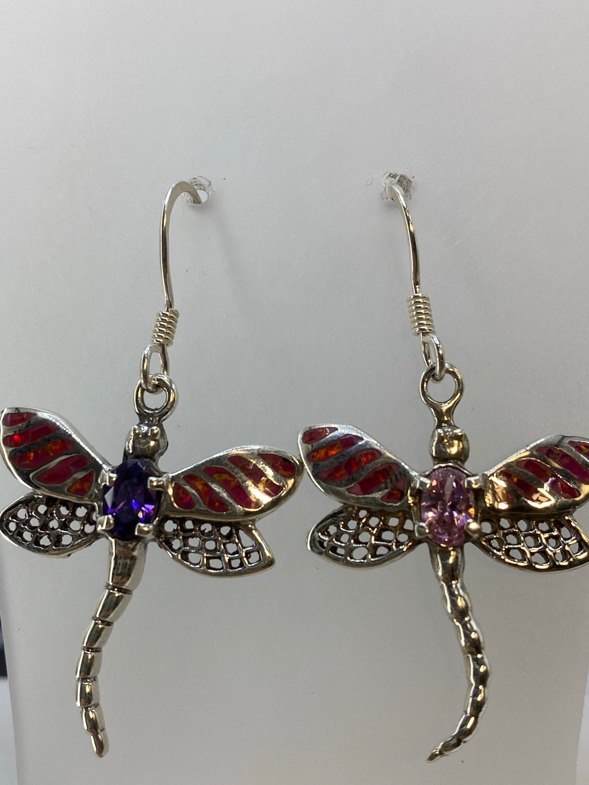 Aretes de ópal de fuego en la mano, 4.5 cm de largo, luz natural acentuando el juego del color